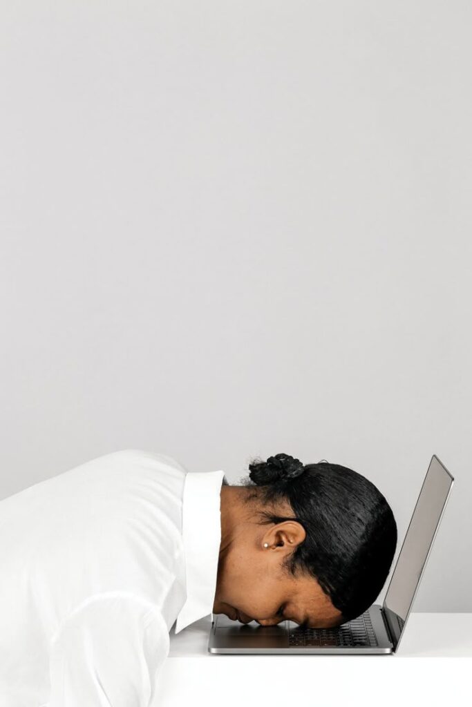 image of Tired black woman resting her head on a laptop.
